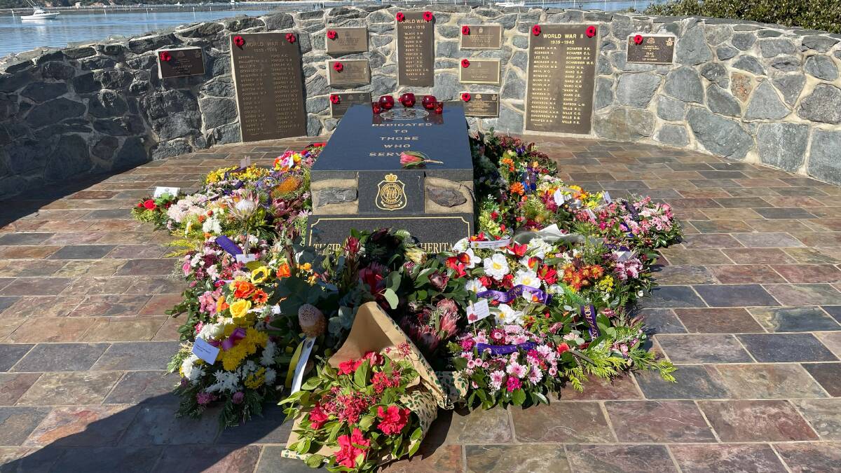 Wreaths surround Merimbula War Memorial while hand-knitted poppies made by CWA are placed across plaques. Picture by James Parker