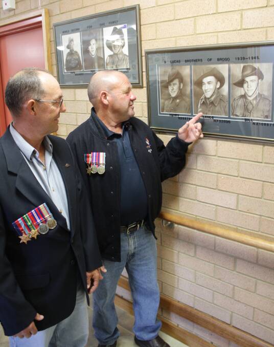 In this photo from 2010, Geoffrey (Hedley) and Henry Lucas, proudly wearing their father’s medals, admire a  photo of their dad, Lance.