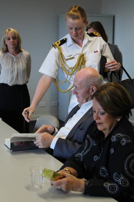 Governor-General Sir Peter Cosgrove signs his book while Lady Cosgrove looks at Timor Leste coffee sold locally.