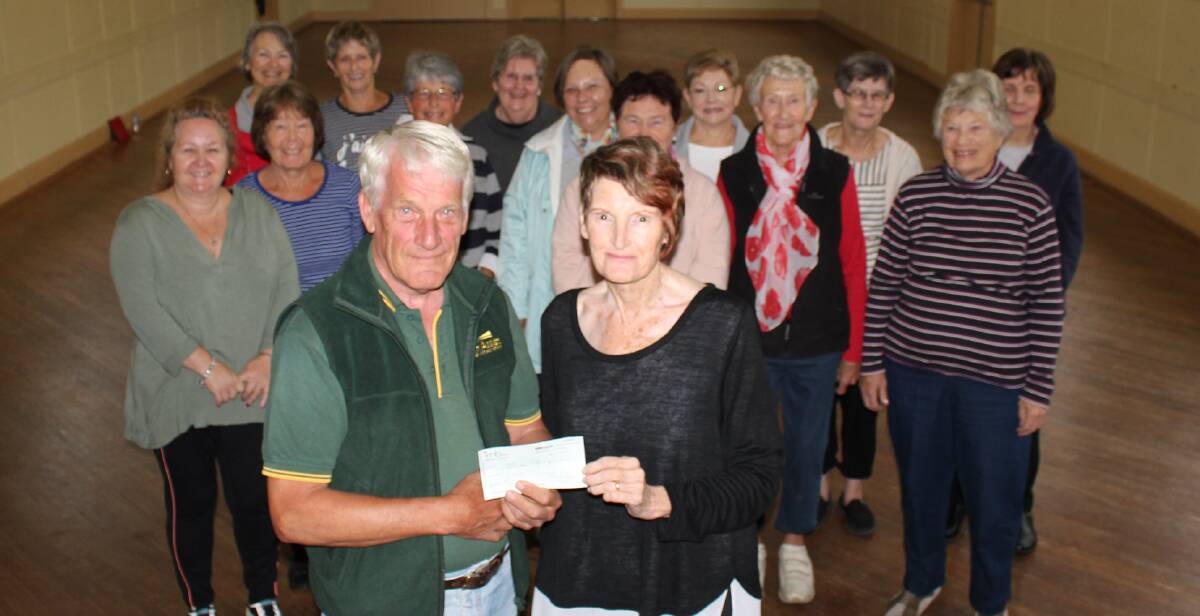 DONATION: Peter van Bracht of Bega Can Assist receiving a cheque from tai chi teacher Maureen Ryan with the Pambula group she teaches.