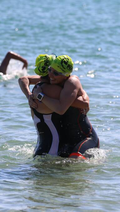 WE'VE DONE IT: Friends share a hug to celebrate the Wharf to Waves just before the finishing line in the 40-49 year age swim at Tathra Beach on Sunday.