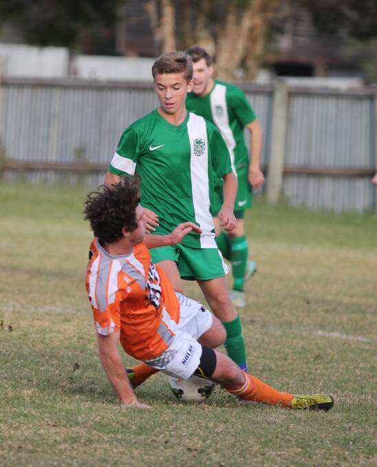 Surprise upset: A Penguin slides for the ball under his Merimbula opponent on Sunday with the Grasshoppers sneaking a come-from-behind win. 