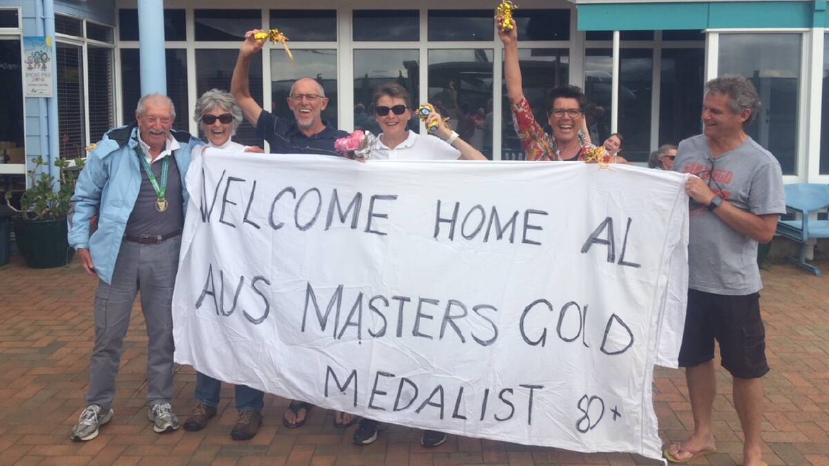 GOLDEN ARRIVAL: The Bar Beach swimming group welcomes gold medallist and fellow member Alan Cameron at Merimbula Airport. Photo: Submitted.