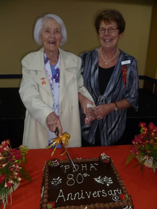 Patron of the Pambula District Hospital Auxiliary, Janet Gill cuts the anniversary cake assisted by Marion Dickins, state president of the United Hospital Auxiliaries. 