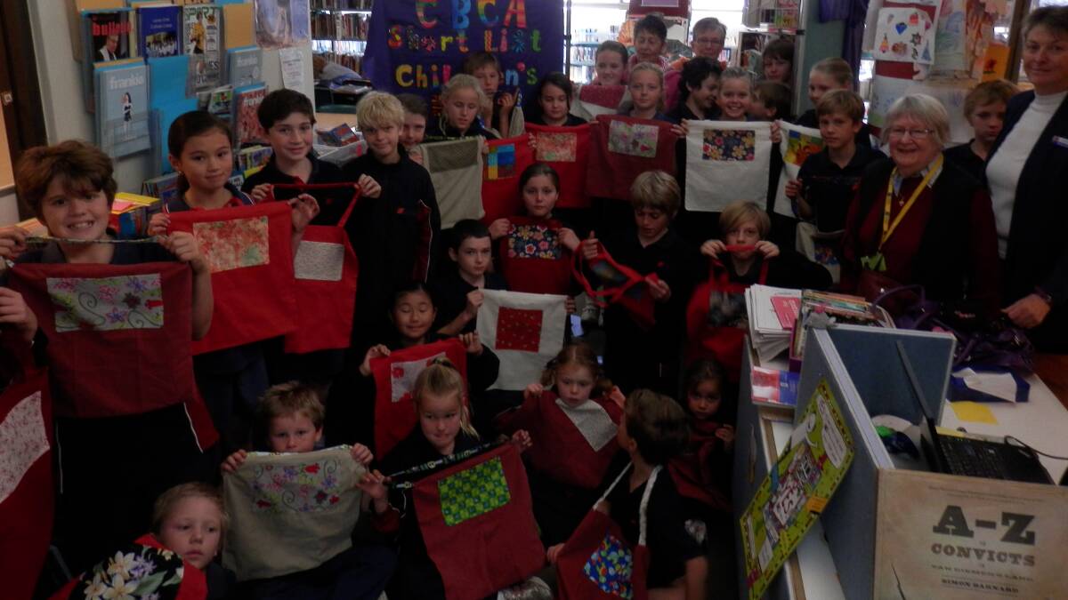 Photo is of the Lumen Christi Junior students in their library, showing off their library bags, with, at rear Susan and Rose, and on the right Pat Ingram and librarian Michelle Bootes. 