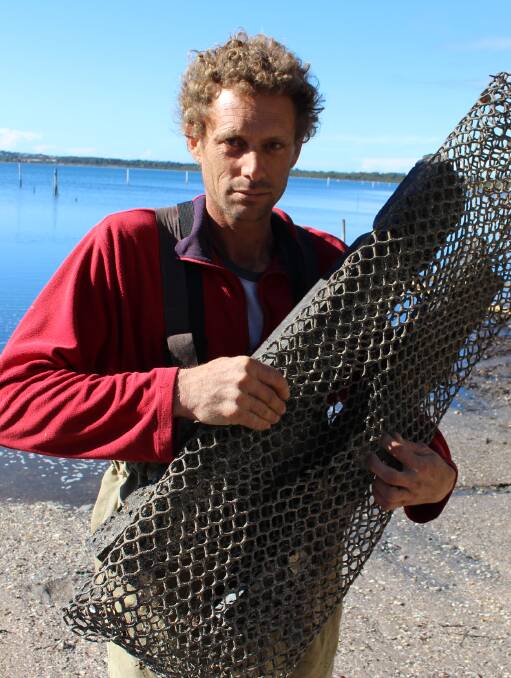 Frustrated: Dominic Boyton of Merimbula Gourmet Oysters holds up bag that has been slashed with a knife in order to steal the oysters inside. Picture: Melanie Leach