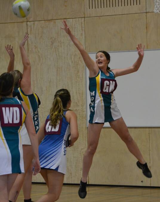 High flyer: Maroon goal keeper Romy Cook jumps high to deflect a shot by the black goal attack in Monday night's netball grand final.