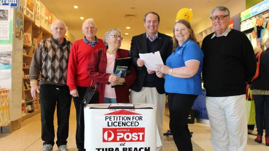 Tura Beach residents John Brassington, left, John Jacobsen, Else-Marie Hoyland and Milton Black with Dr Peter Hendy and Tura Beach Newsagency owner Sherrill Trehearne with the petition for a fully functional post office in Tura Beach. 