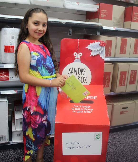 Santa is coming: Year five Merimbula Public School student Chloe Ghattas has put her Santa letter in the Merimbula post office's mail box and can't wait to receive a response. Picture: Melanie Leach