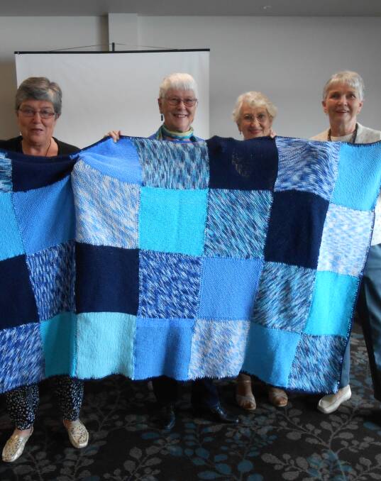 Charity: Merimbula Knitwits Di Waldon, Anita Paget, Judy Carton and Heather Williams show their completed Wrap with Love blanket to the Merimbula Probus Club. 