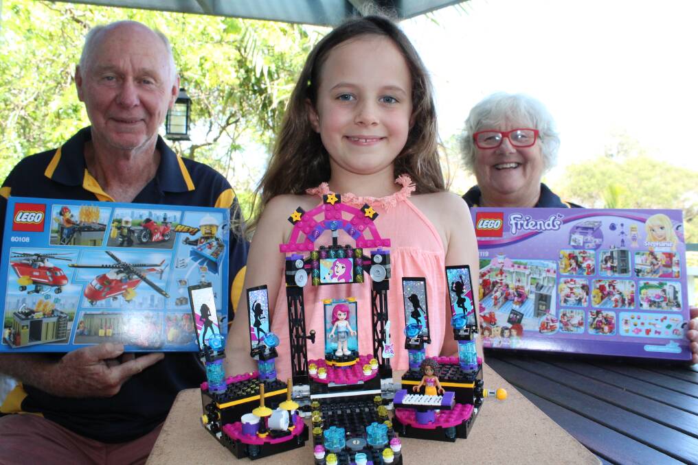 LEGO FANS: Pambula Rotarians Steve Goodchild and Lee Beatty with seven-year-old Scarlette Culliver who is holding an impressive display she built mainly by herself but with "a tiny bit of help from mummy". Picture: Melanie Leach