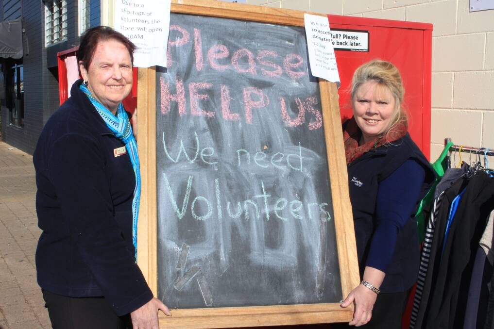 Help needed: Merimbula Salvation Army Family Store managers Carole Davis and Sue Davidson hold up a large sign placed outside the store calling for more volunteers. 