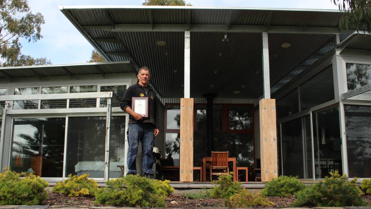 Mr Briggs out the back of the stunning Millingandi home holding his MBA Excellence in Regional Building Award. 