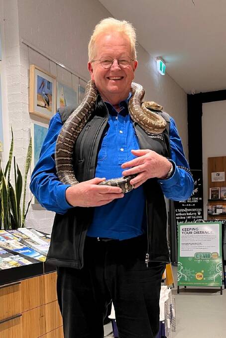 Chris Nicholls in his element at the Merimbula Visitor Information Centre, holding a python from the Tiny Zoo. Photo supplied. 