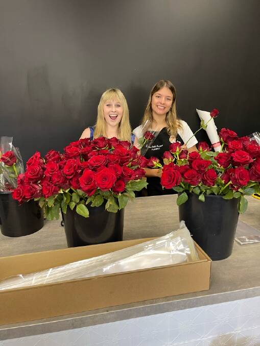 Jasmine Fleet and Marlee Ahmat preparing the single wrapped red roses on Valentine's Day. Picture supplied. 