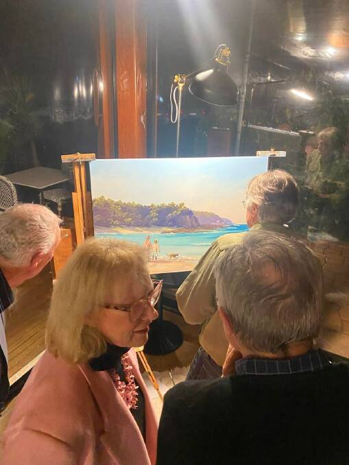 Guests gathered round the finished copy of the artwork created by Glenn and Ann Morton at the Wheelers fundraising live art event for Bega Valley Can Assist. Photo supplied. 