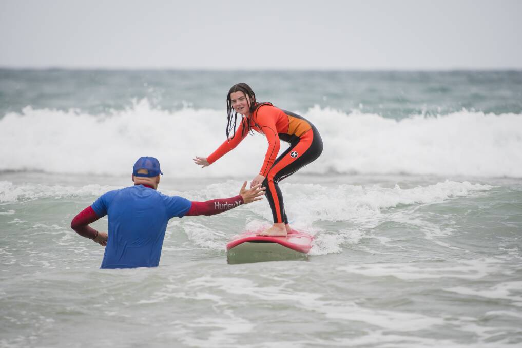 Broulee Surf School head coach Shane Wehner high fives surfing student Alex Kemp. Picture by Sitthixay Ditthavong
