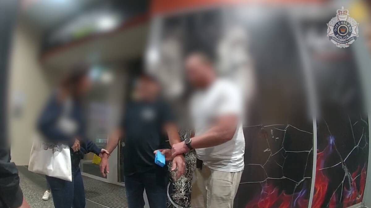Taskforce Argos detectives pull what appears to be a box of Lifestyle condoms from the suspect's pocket. Picture via QLD Police