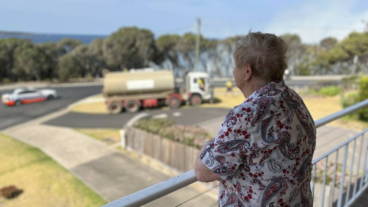 Jan Blaxter watches emergency services attend to a fire in the vicinity of Aslings Beach in Eden NSW, September 19, 2023. Picture by James Parker