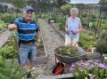 Pambula Village Community Garden member Jim Eberbach and president Rae Joyce within the beautiful gardens in the heart of Pambula, surrounded by blossoming flowers and yet-to-be collected vegetables. Picture by James Parker