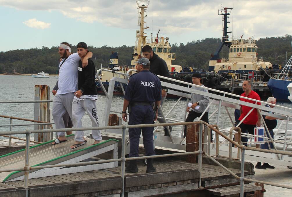 Passengers are escorted off Carnival Legend by Marine Area Command police.