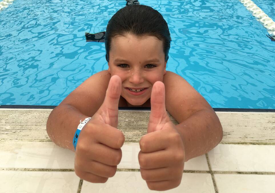 STOKED: Isaac Donne, 7, gives the thumbs up during his efforts to swim 99 laps of Pambula pool to raise $99 for a homelessness charity.