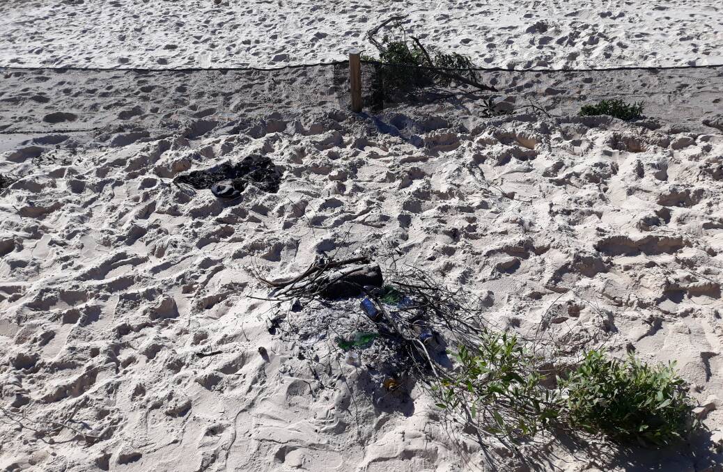 A concerned resident sent in this photo of fire remnants, bottles, cans and litter left in the fenced off section of Pambula Beach near the viewing platform.
