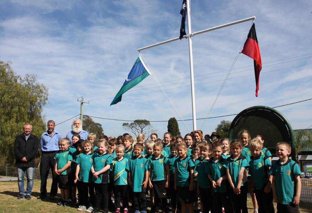 Flying high: The pupils of Wolumla Public School sang the national anthem under their new school flags for the first time on Wednesday morning. Photo: Alana Beitz