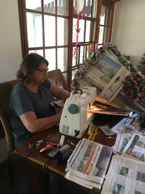 A work of art and craft as Janice Johnson sews newspapers together for her daughter's dress to be worn on Thursday at Breakfast at Tiffany's.