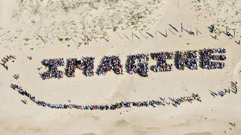 More than 3000 people form one of two human signs on Tathra Beach in 2006, demonstrating the community’s commitment to renewable energy.