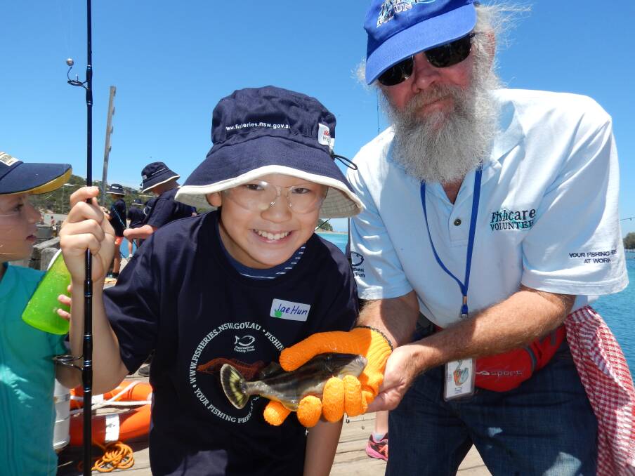 Hooked on fishing: Junior angler Jae Hun Shim with his leatherjacket catch held by Fishcare volunteer Malcolm Campbell