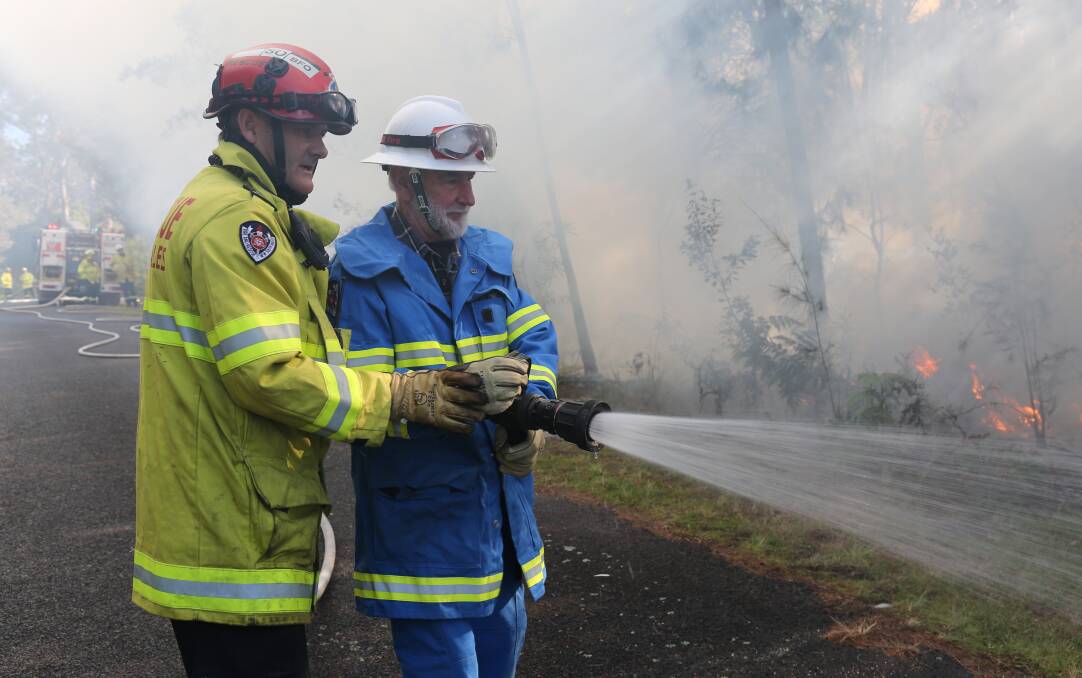 Bushfire officer Greg Rood shows Community Fire Unit volunteer Mal Robinson how to black out the fire during a controlled burn at Tura on Saturday. 