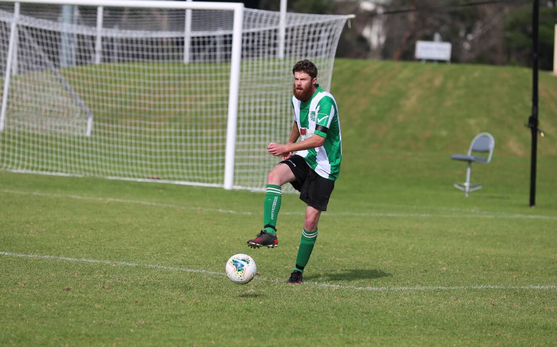 A Merimbula defender fires a kick back into play during the Grasshoppers' 6-1 win over Wolumla on Sunday. 
