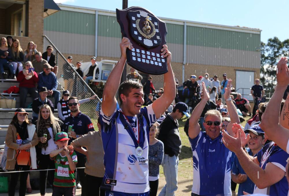 Glory: Rueben Smahel holds the under 18 premiership shield high with team mates and club president Laurie Delle Vergin cheering.