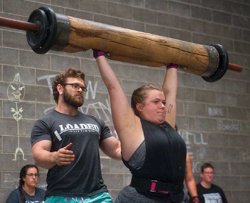 A competitors hoists the log high during a recent competition with the Iron Stronghold hosting a strongman event this Saturday. 