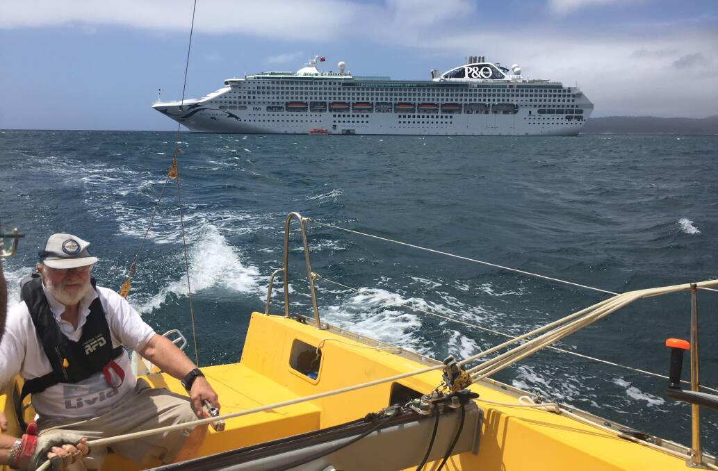 Scenery: Twofold Bay Yacht Club vice-commodore Ted Dexter at the helm of Livid with the P&O Pacific Explorer as a backdrop for a sail on Sunday. 
