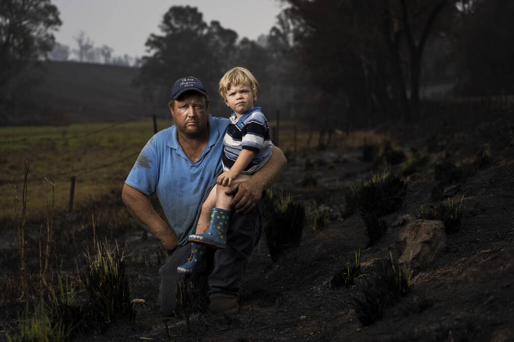 Aaron Salway, with his nephew Harley Salway, 2. Just behind them is the ridge where Aaron's father Robert, and brother Patrick Salway died protecting their property in Wandella. Picture: Dion Georgopoulos