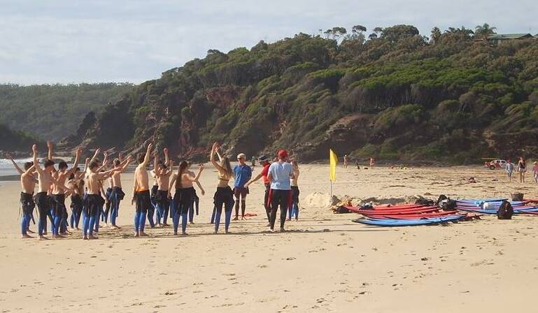 German exchange students limber up before a surfing lesson at Pambula Beach.