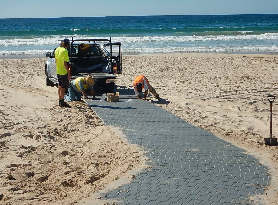 Wheelchair friendly: VIROtech and Replas staff installing the new assisted access ramp which now reaches the high water mark at Pambula Beach.